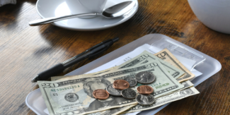 U.S. dollar bills on top of a restaurant check on a wooden table