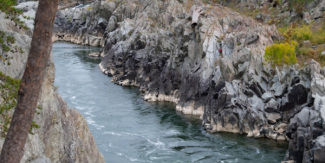 Great Falls flowing through a rocky gorge with steep gray cliffs and surrounding trees