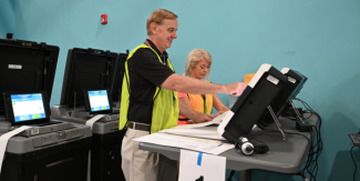 Image of election officers operating a ballot scanner. 