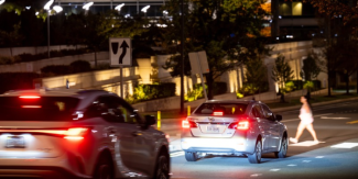 pedestrian crossing the street at night in traffic