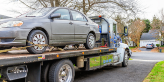 A car getting towed from a driveway