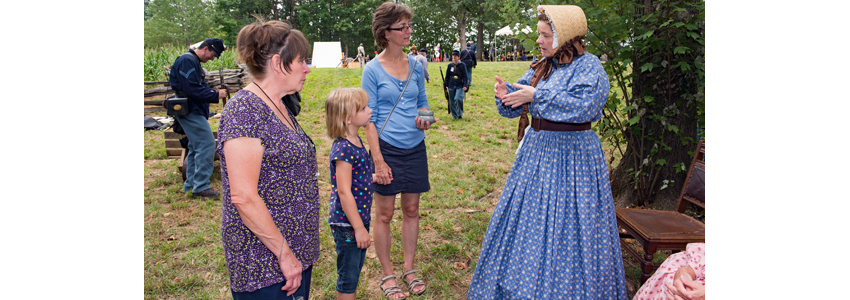 Costumed female re-enactor speaks with park visitors