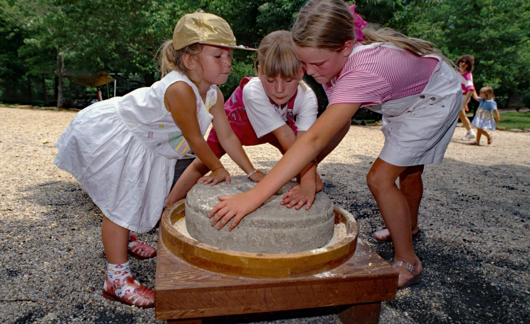 Children try to turn a grinding stone