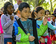 A young boy learns about American Indian games by aiming a feathered corn cob at a ring