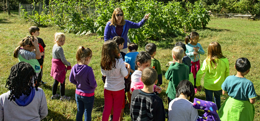 Naturalist speaks to a group of children in a field