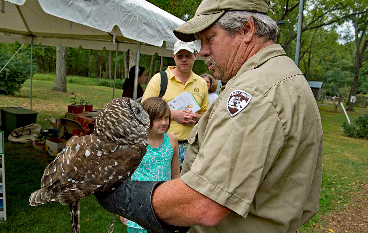 Naturalist holds an owl on his arm while a young girl looks on