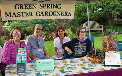 Master Gardeners sit at a help desk with multiple brochures
