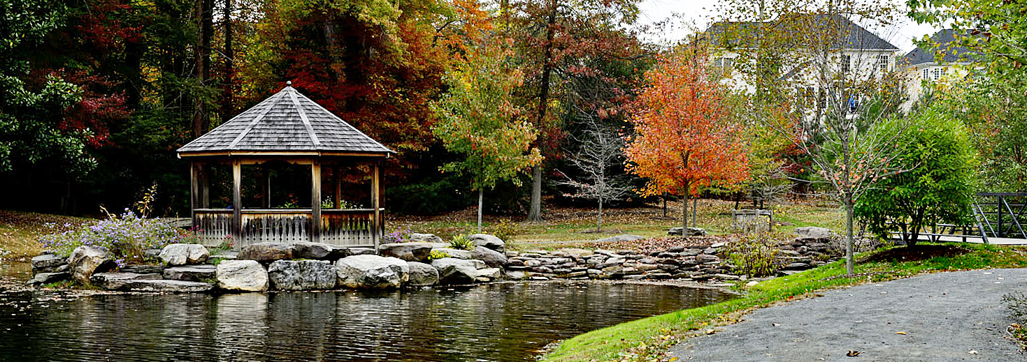 A gazebo stands on a point of land sticking out into a pond