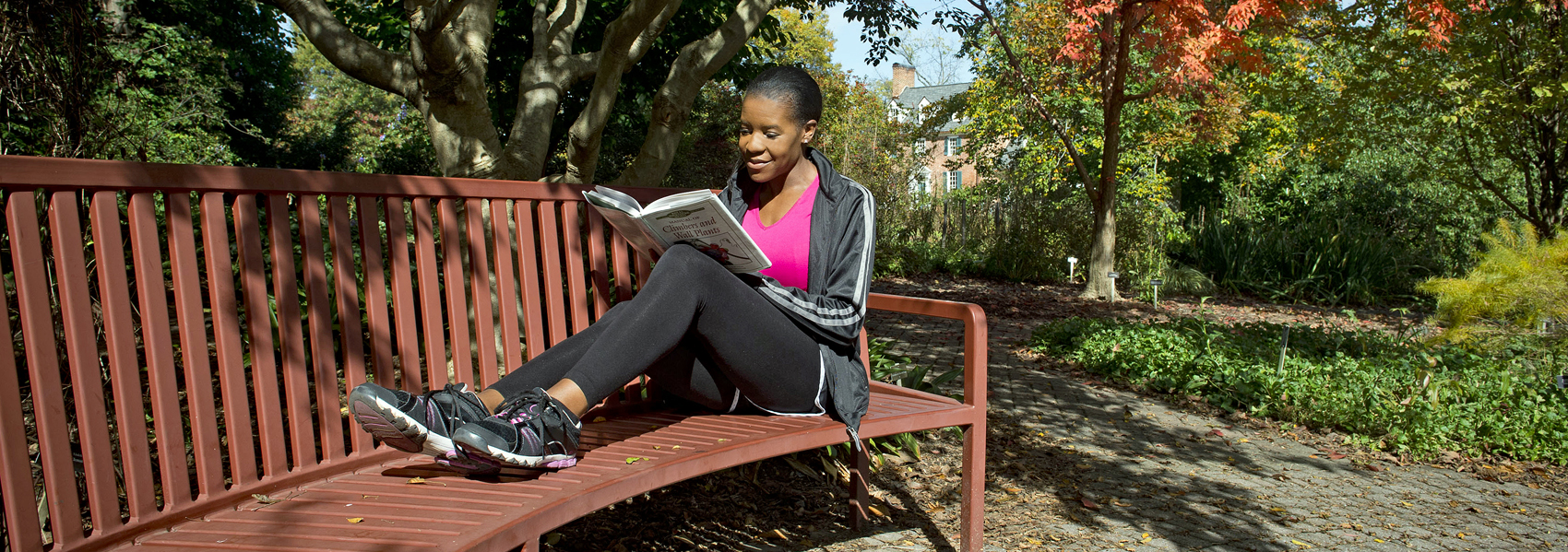 A woman reads on a bench in the gardens