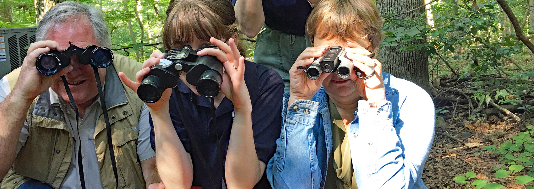 Three staff members post with binoculars