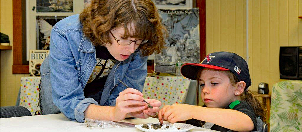 A volunteer guides a young boy in a craft project