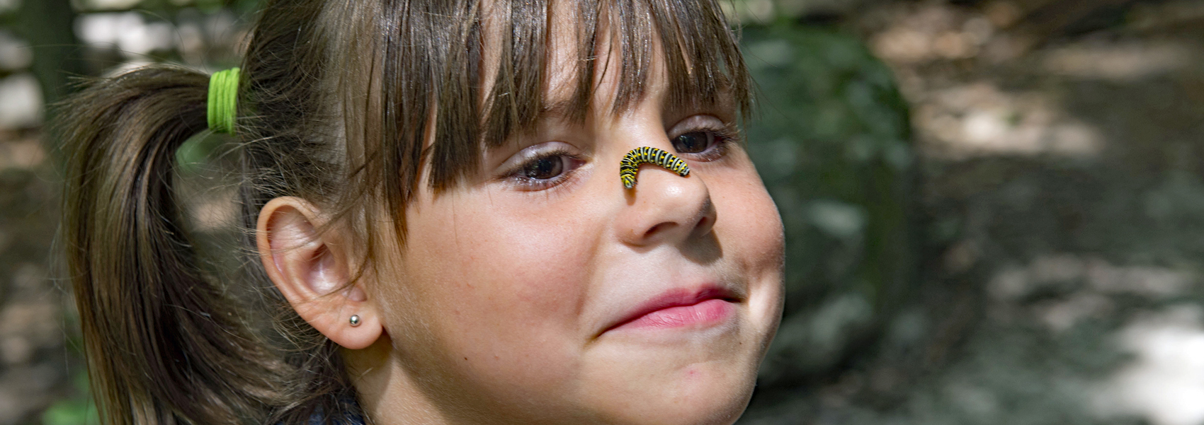 A caterpillar crawls across a young girl's nose