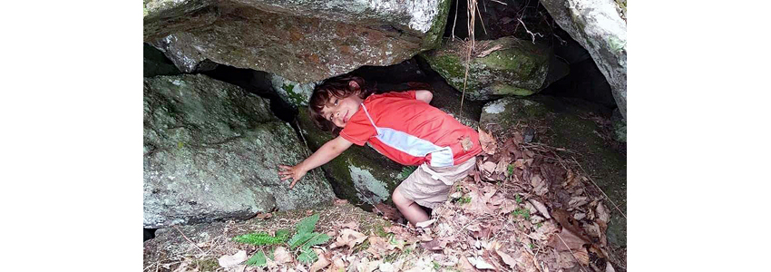 Child bends into a small rock cave