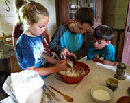 Docent in cook's costume helps youngsters beat biscuits