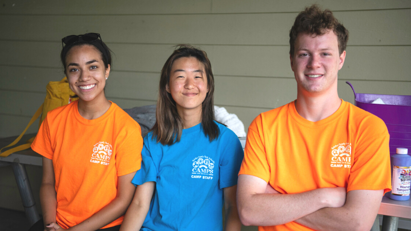 three Fairfax County Park Authority employees working while wearing their bright camp t-shirts