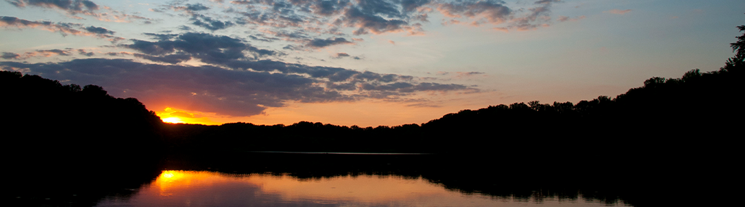a landscape view of the sun setting over the lake