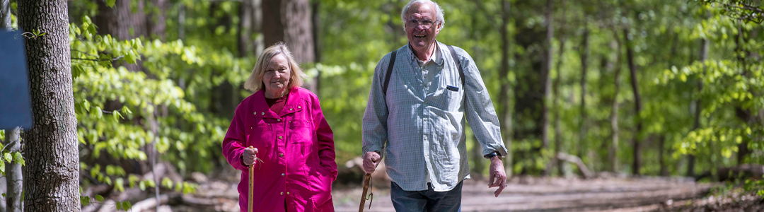 an older couple walking with walking sticks on one of the Fairfax County Park Authority walking trails