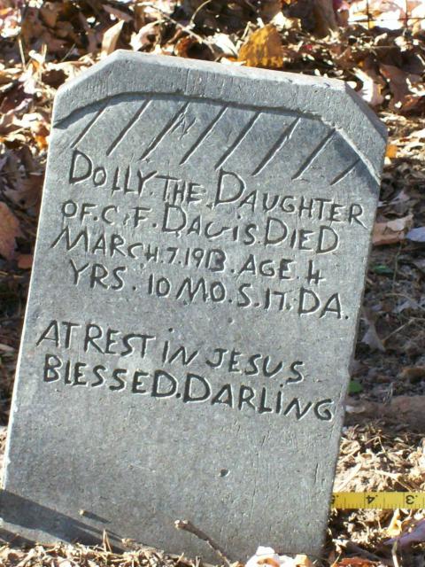 a stone headstone with text etched in that reads DOLLY THE DAUGHTER OF C.F. DAVIS DIED MARCH 7 1913