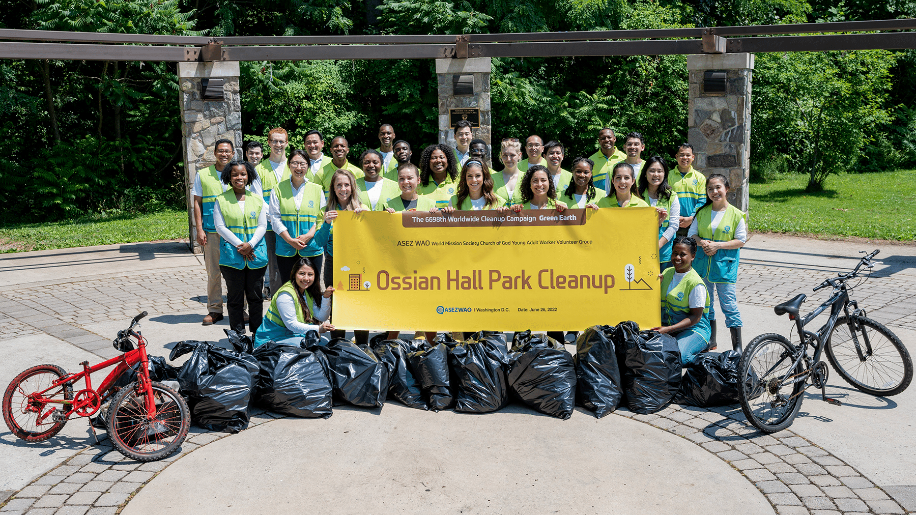 a bunch of people wearing high-visibility vests, standing around a sign that reads Ossian Hall Park Cleanup
