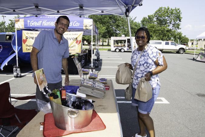 a farmers market vendor and a person holding bags of market goods