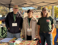 four volunteers in front of a market managers tent at a farmers market