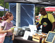 a vendor at a farmers market helping a customer