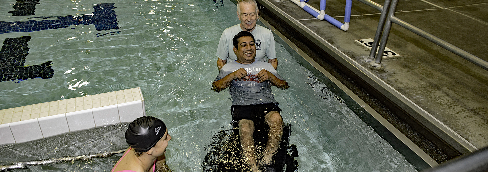 Volunteer helps swimmer in wheelchair into pool