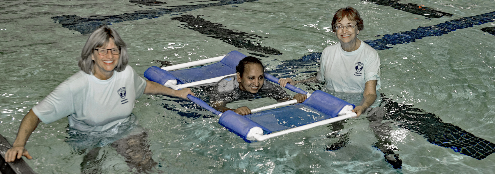 Adapted aquatics volunteers with swimmer in floating frame