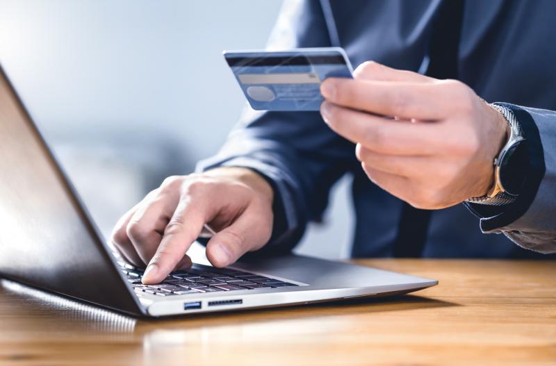 man holding credit card while on laptop