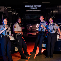 4 police officers stand in front of police car