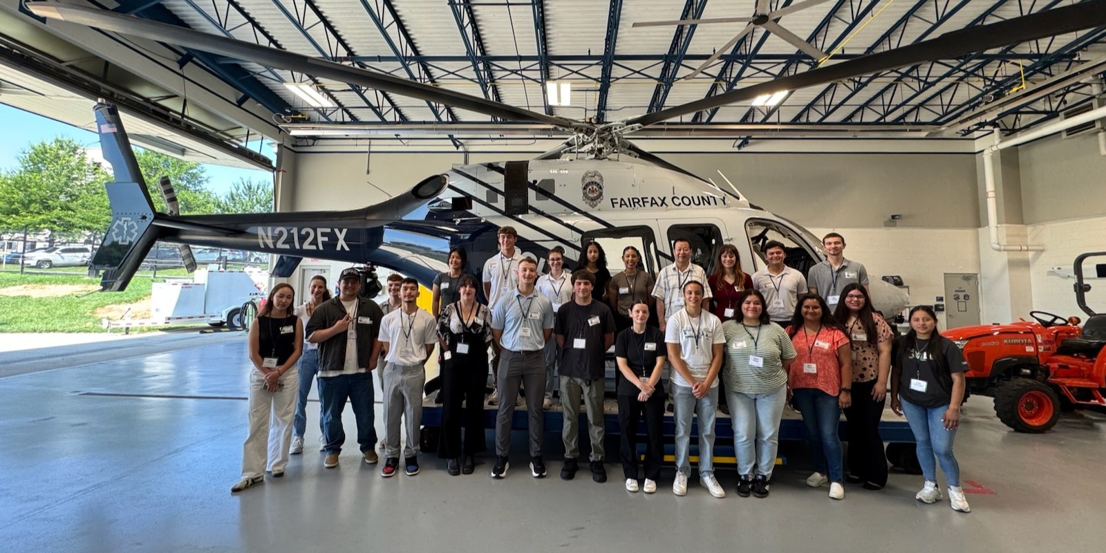 group of young adults standing together in front of a fairfax county police helicoptor