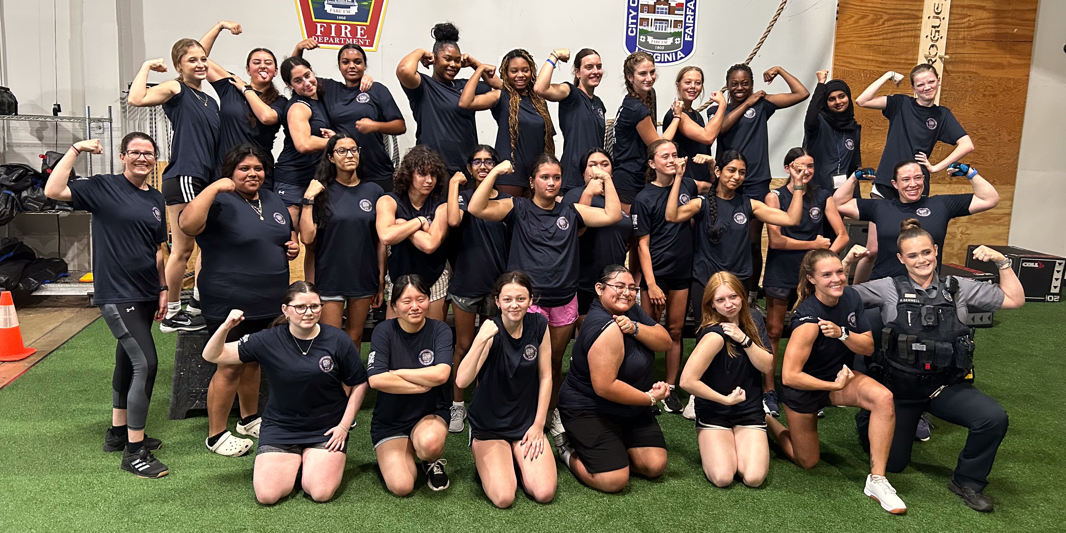 group of girls with a woman officer posing together with arms flexing pose