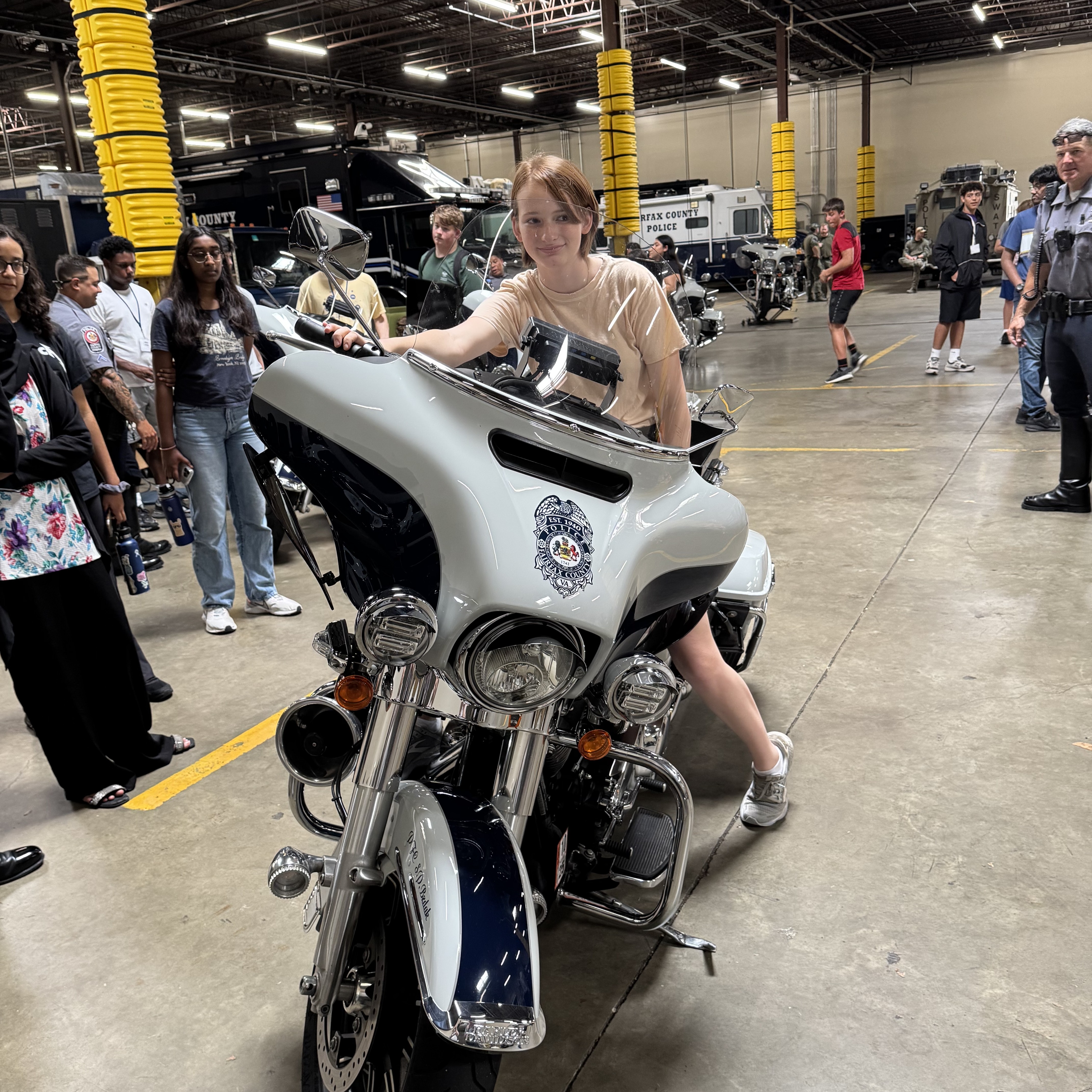 young teen supervised while posing with a police motorcycle