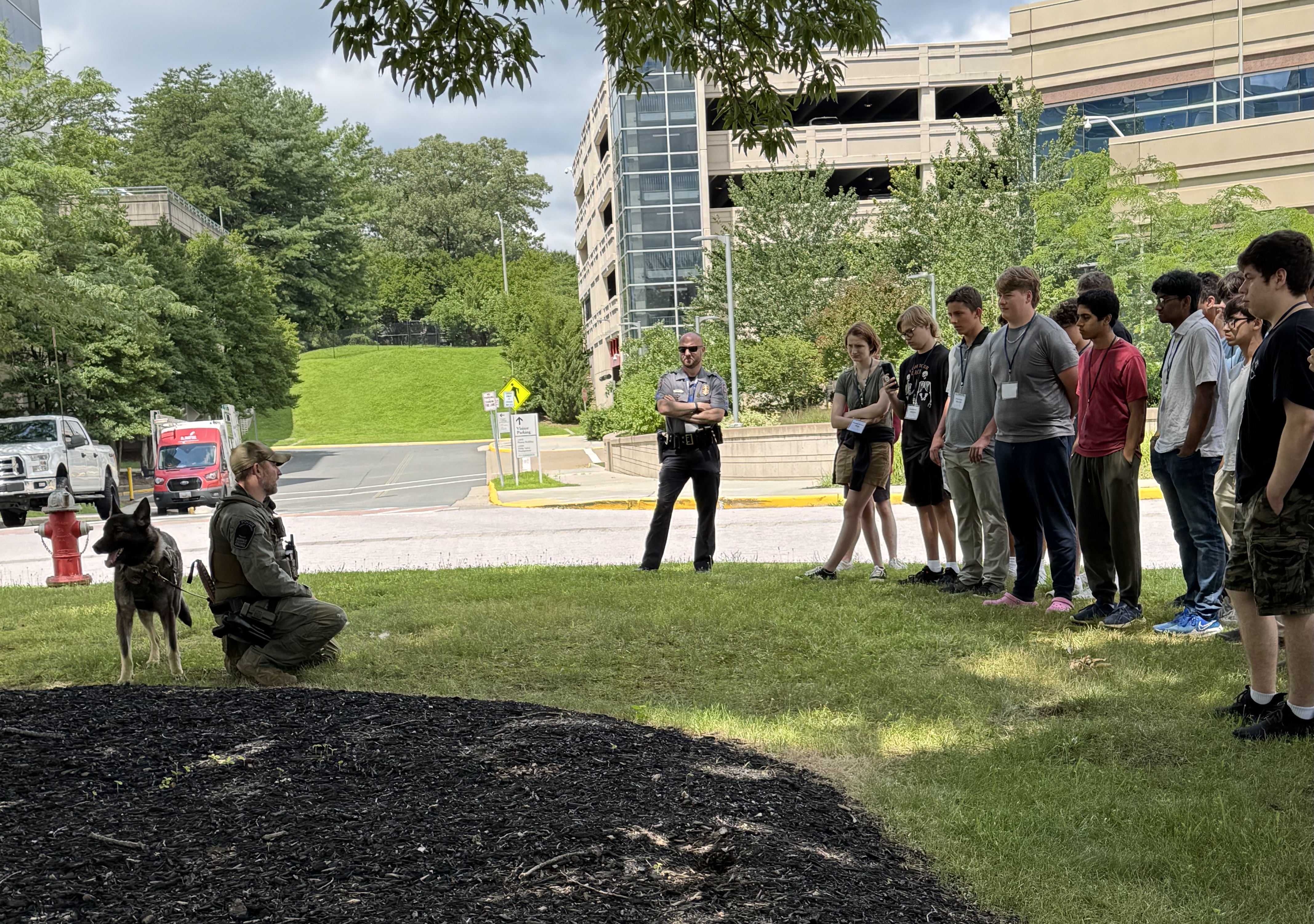 K9 officer and their working dog presents information outdoors to teens