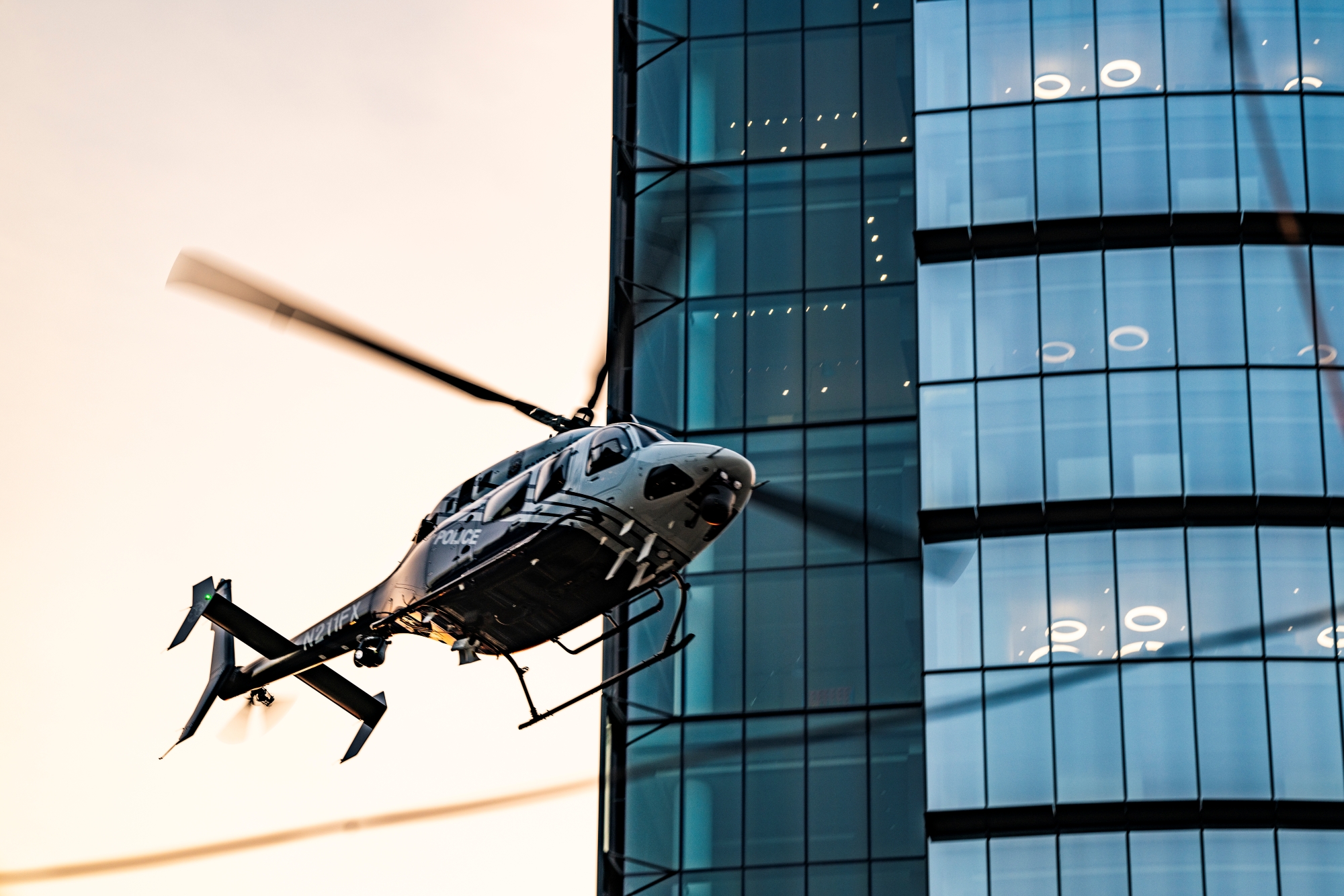 Fairfax 1 helicopter (tail number N211FX) banking past a glass office tower
