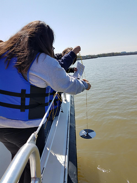 A teacher tests the turbidity of the Potomac River from the Chesapeake Bay Foundation's research boat.