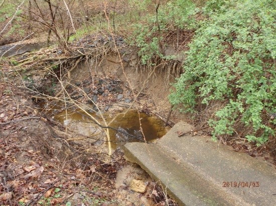 Collapsed concrete ditch at a storm drain outfall creating more than a 4-foot cut into the stream bed