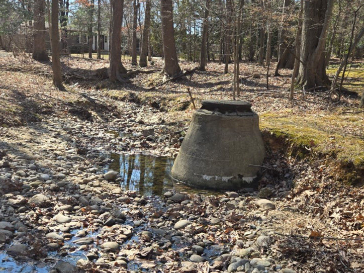 Exposed sanitary sewer manhole within the stream channel because of channel incision and bank erosion. 