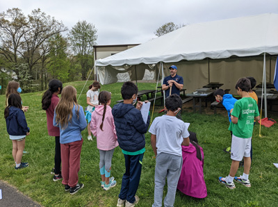 An ecologist engages with several students outside.