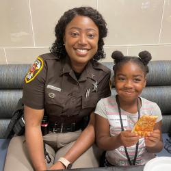 deputy sheriff and little girl enjoy pizza