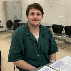 Harley sits at a table during peer recovery specialist class