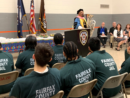 Dr. Michael Nickens holds tuba and speaks to inmates