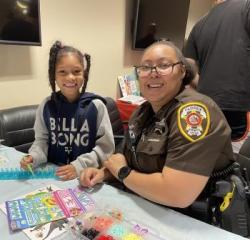 Deputy sheriff and young girl work on craft projects.