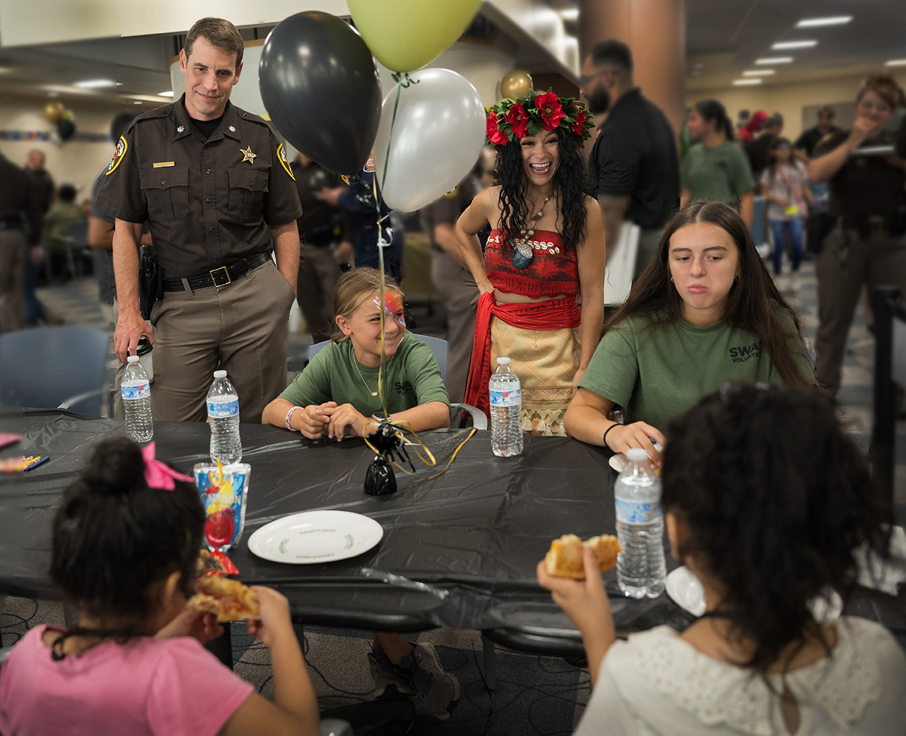 Sheriff deputy Lt. Col. Casey Lingan (left) listens to lunch conversation between “Moana,” volunteers and two girls from a local shelter as they enjoy Paisanos Pizza, Aug. 12, 2025. 