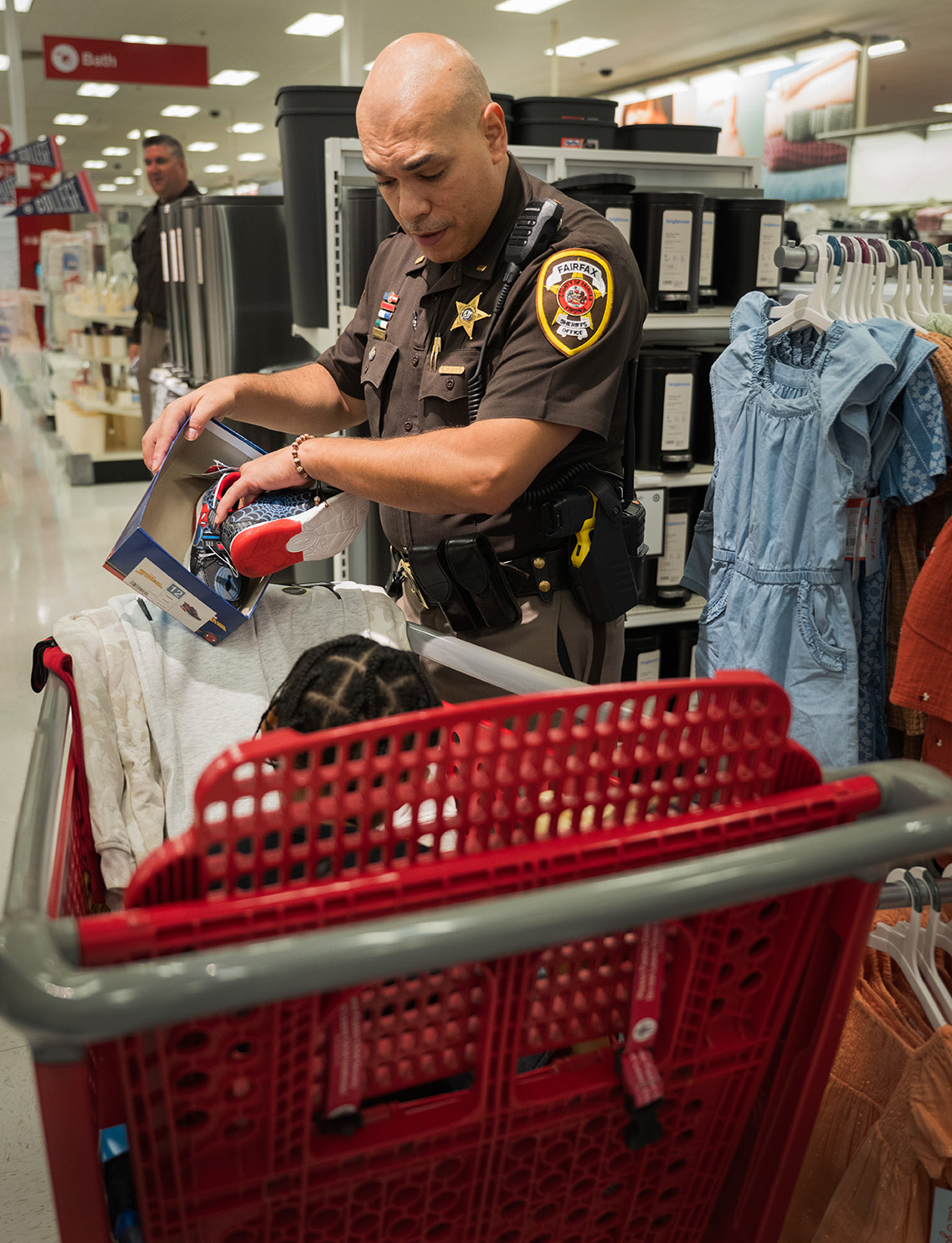 Sheriff deputy 2nd Lt. Jesse Hernandez helps a child try on a shoe during the annual Shop with a Sheriff event in Burke, Va., Aug. 12, 2025.