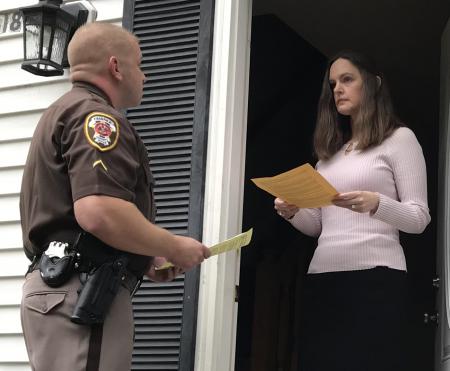 Deputy serves document to woman at house.