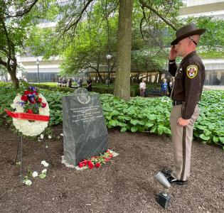 Deputy salutes at memorial after laying a rose.