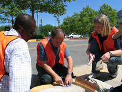three people apply a storm drain label