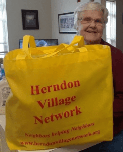 person holding Herndon Village Network yellow bag