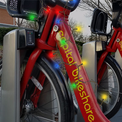 A docked Capital Bikeshare bike, wrapped in a string of colored lights